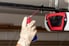 gloved hand applying oil to garage door chain