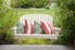 White porch swing and throw pillows with yard in the background.