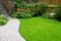 A landscaped space with a curved paver walkway and lush lawn.