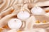 Small, white tea light candles on gold satin fabric.