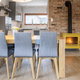 dining room with exposed brick, woodstove, and upholstered chairs at a long table