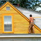 a triangular yellow house with a person standing on the roof