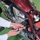 A person performing basic maintenance on a red motorcycle.