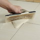 Spread grout into tile joints on the floor.