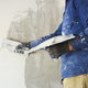 A DIYer plastering a concrete wall.