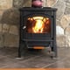 small wood stove on hearth pad in front of stone wall