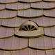 A stylized roof vent surrounded by matching brown tiles.