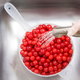 Cherries in a colander being washed with a kitchen sink sprayer.