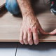 hands installing click flooring over tile