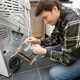 A technician working on repairing issues with a dryer.