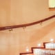A lit, curved stairway with a handrail mounted on the wall.
