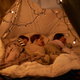 Kids asleep in a blanket fort.