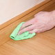 dusting wooden baseboard with cloth