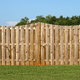 A wooden fence on a lush green landscape against a bright blue sky.