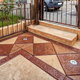 A beige and brown stamped concrete patio surrounded by a metal fence.