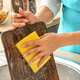 hands cleaning cutting board with sponge