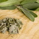 Fresh and dried sage leaves lay on a cutting board.