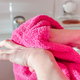 A woman uses a pink hand towel.
