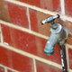 An outdoor faucet attached to a brick wall.
