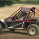 A dune buggy driving on a dirt track.