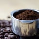 tin of ground coffee resting on top of coffee beans