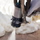 gloved hand spraying foam insulation