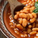 bowl of cooked beans with basil, hot pepper and wooden spoon