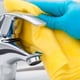 cleaning bathroom faucet with gloves and sponge