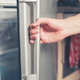 A person opening a refrigerator door.