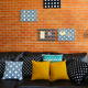 Colorful pillows on a sofa with brick wall in background.