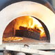 outdoor cement pizza oven with fire and pizza inside