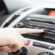A woman presses a button on a car radio