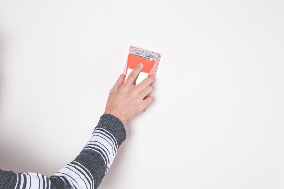 Someone using sandpaper on a white wall. 