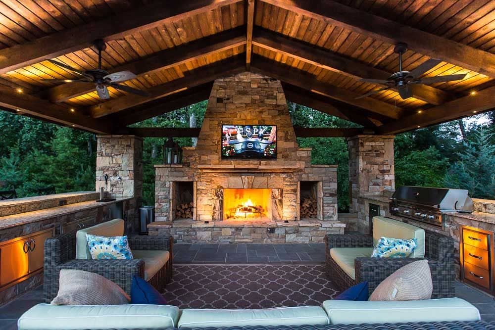 Outdoor kitchen lit up by a gorgeous central fireplace.