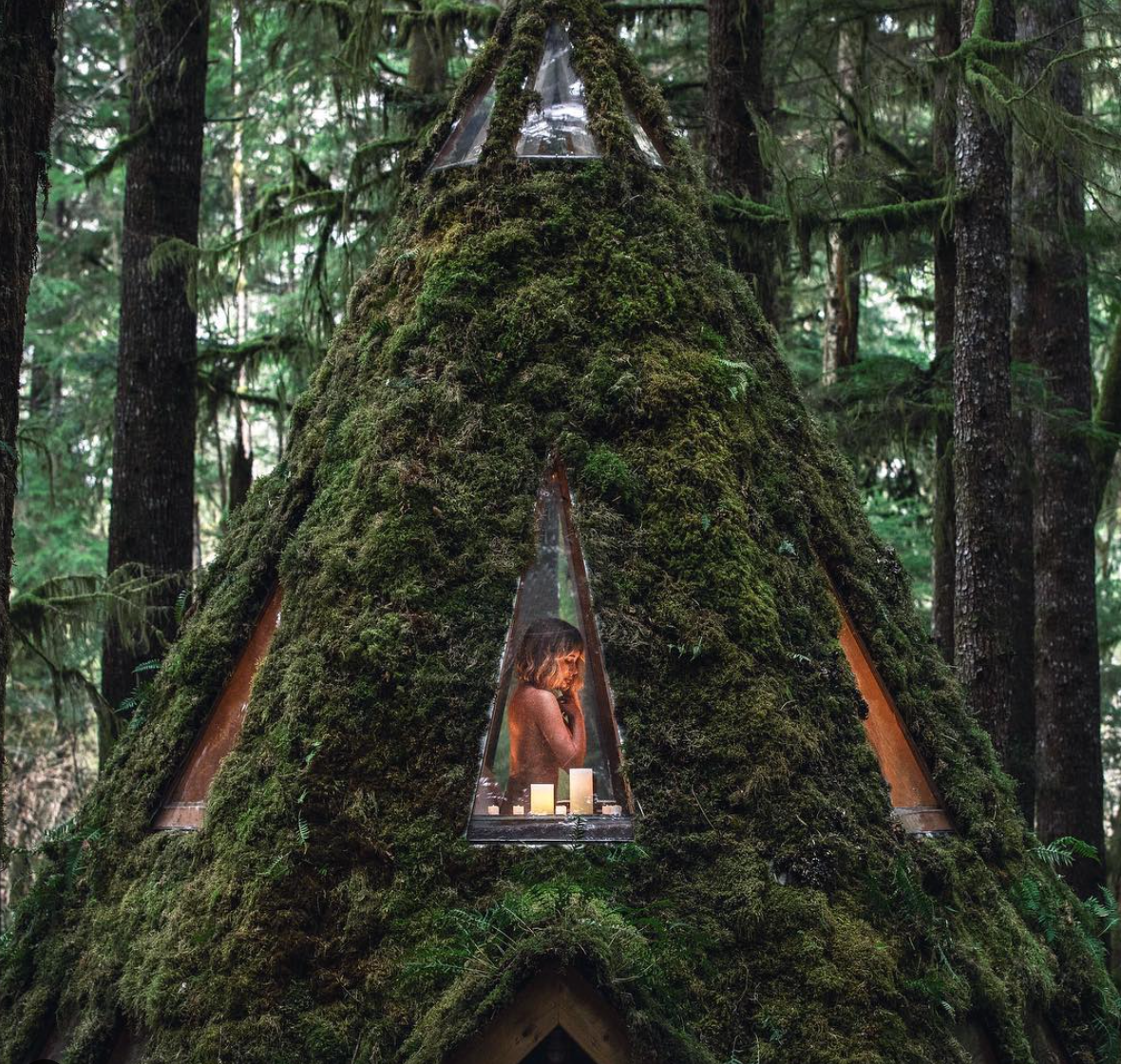 Sara Underwood poses through the window of a magical moss-covered cabin in the Pacific Northwest built by her and partner Jacob Witzling.