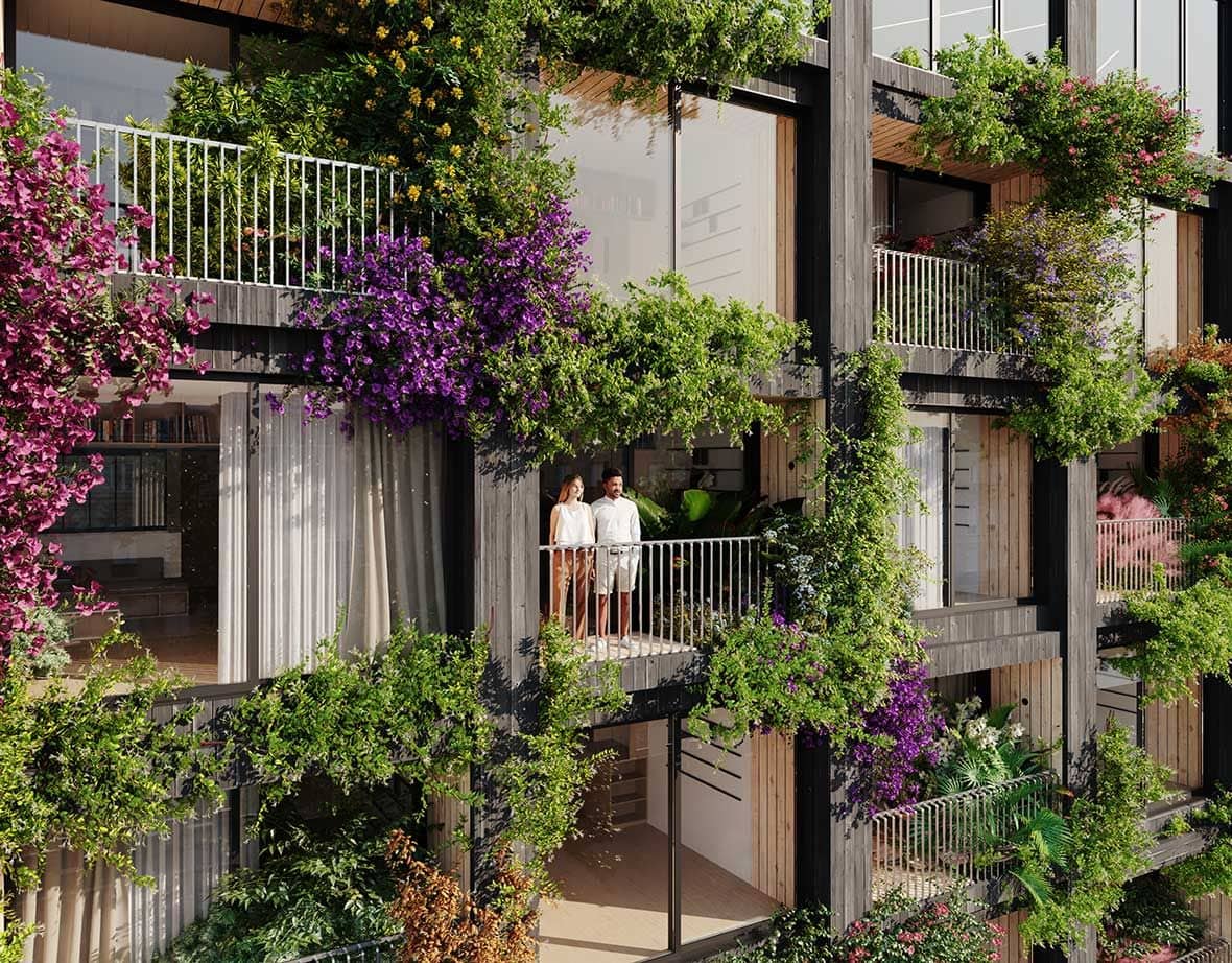 Couple looks out a lush balcony space attached to their Bouyges Immobilier apartment module.