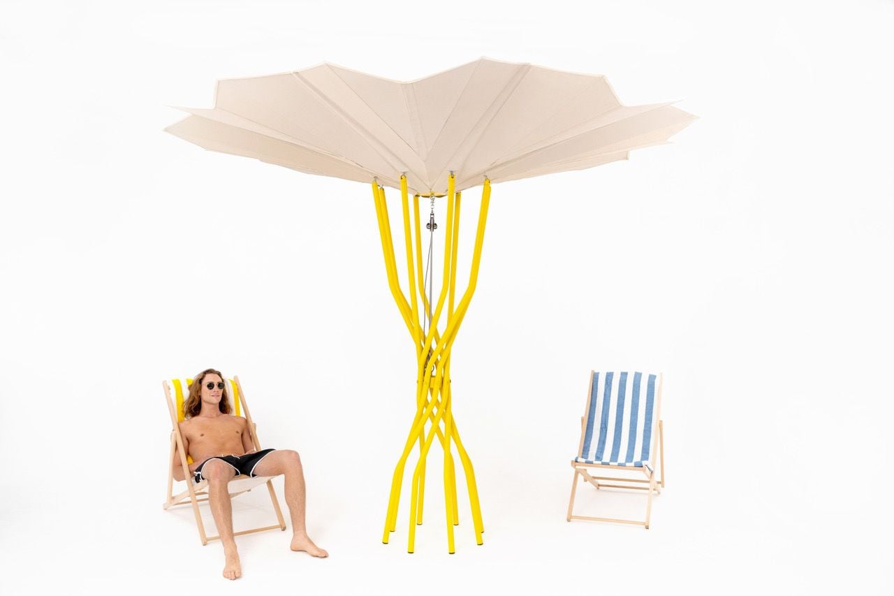 Beach-goer relaxes beneath a Carlo Ratti-designed Sammontana sustainable beach umbrella. 