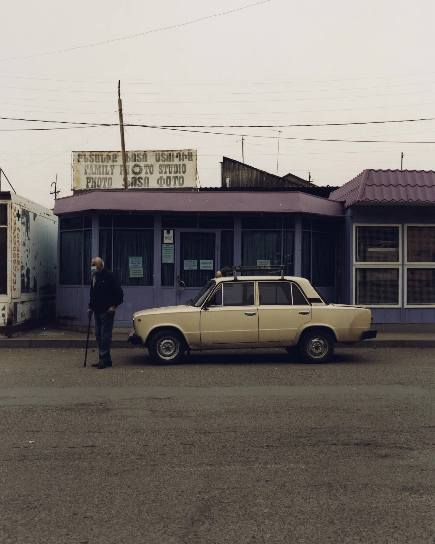 Old man and Soviet-era Lada car outside a photo studio in Armenia.