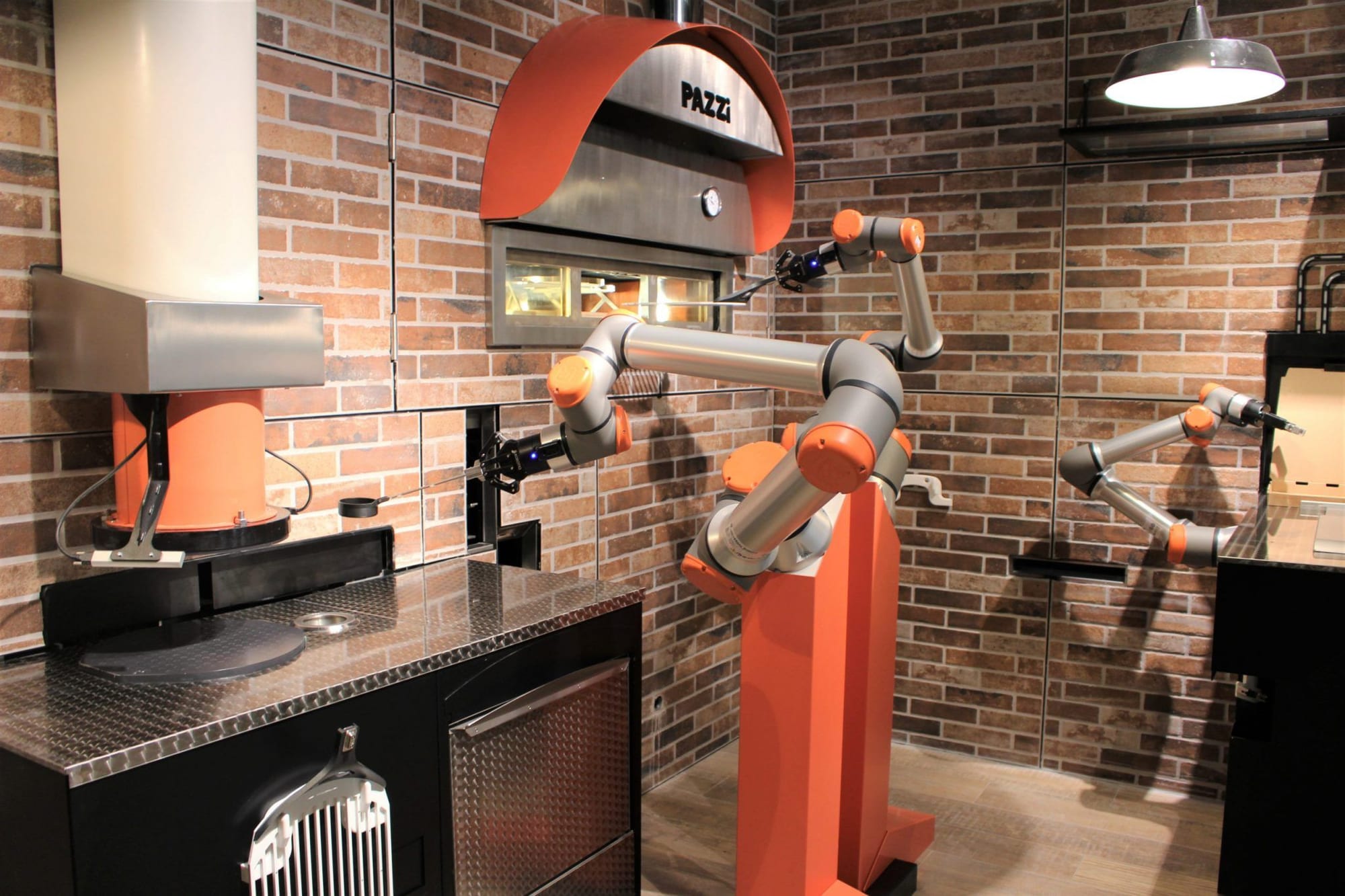 Large orange robotic arm inside Paris' Pazzi pizzeria works hard to whip up some tasty pies. 