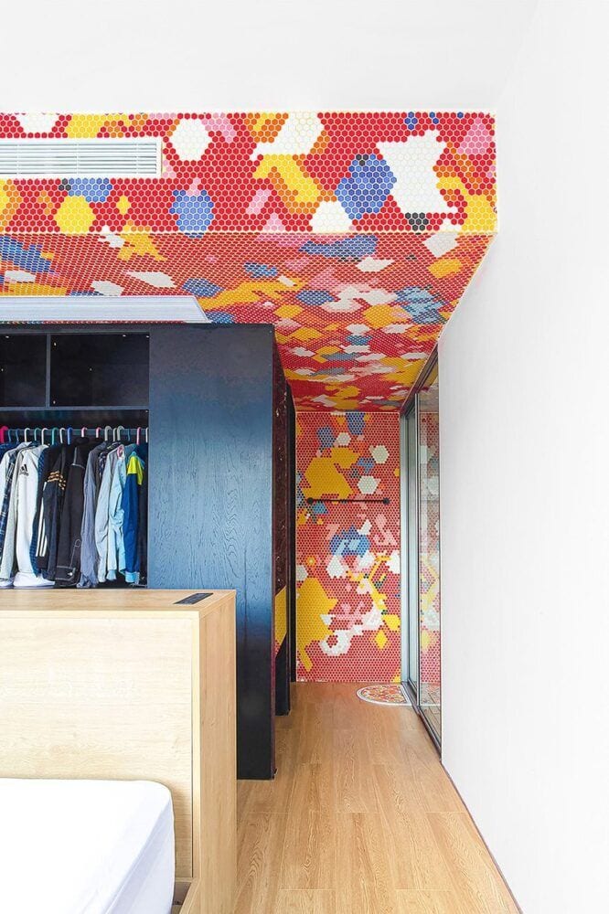 The bedroom walls inside the Live and Fun apartment are similarly adorned in primary colored tile mosaics.