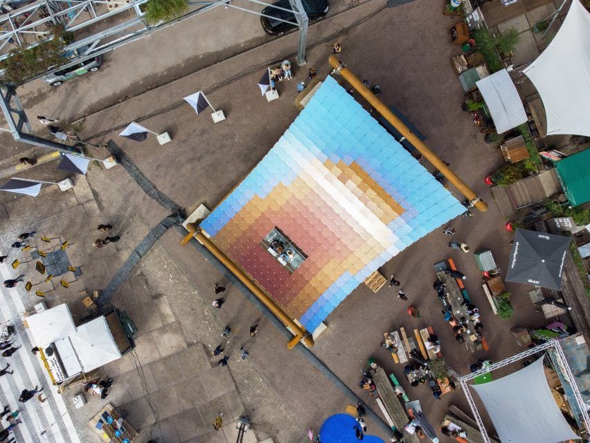 High aerial view of the solar pavilion reveals a design that looks like a sun rising into a crisp blue sky.