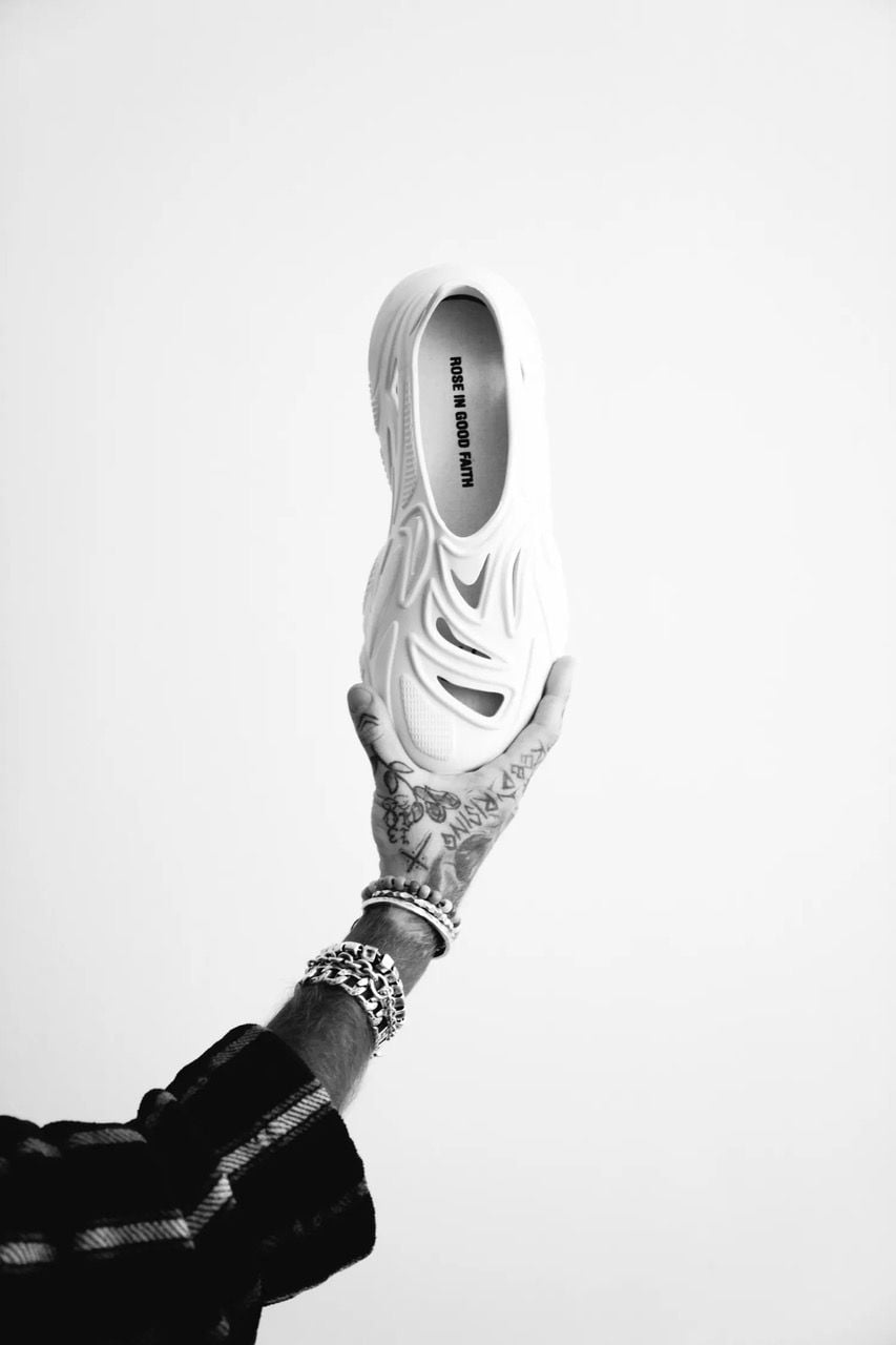 Black and white photo of a hand holding up Rose in Good Faith's upcycled Plastic Soul sneaker.