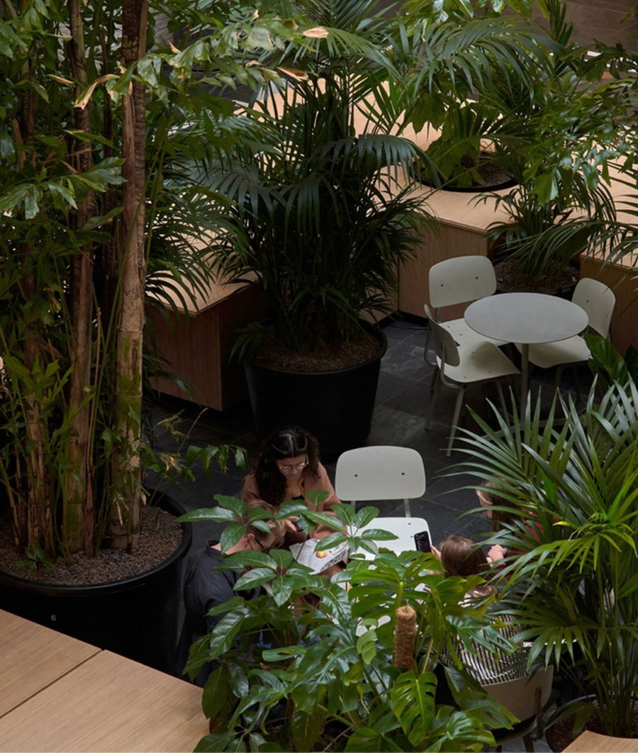 Small café-style tables are hidden among the greenery at the center of the mobile work island configuration. 