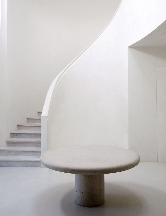 A sleek spiral staircase and round table in Kim and Kayne's all-white LA mansion.