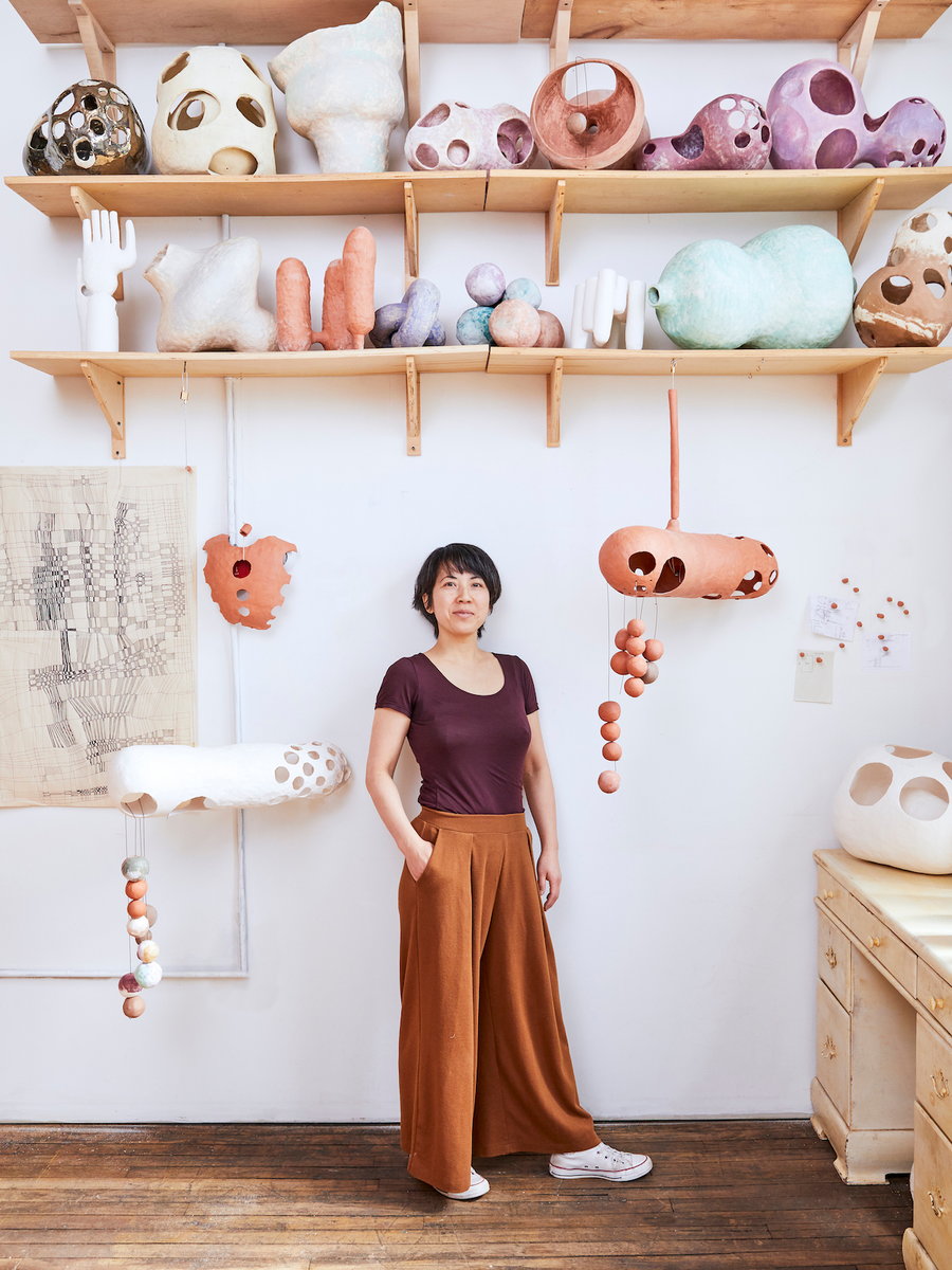 Designer Yuko Nishikawa stands in front of her handcrafted organic lighting fixtures. 