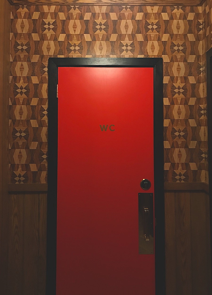 Restroom entry inside the re-imagined Turk's Inn super club, with bold wallpaper lining a bright red door.