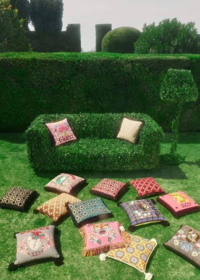 Colorful throw pillows from the new Gucci Décor collection on a couch-shaped hedge.