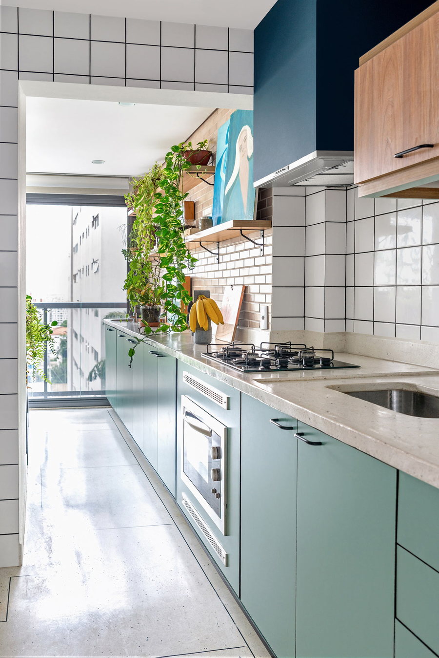 Long kitchen space inside the FM House effortlessly blends greenery and contemporary design features with bold retro touches.