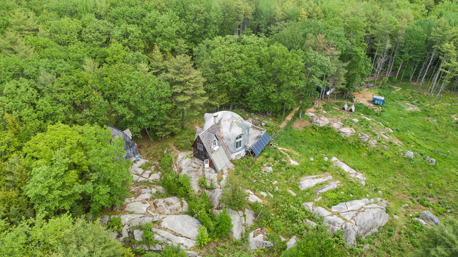 Aerial view shows the 34 Road to Misery Dome Home in its wooded Maine setting. 