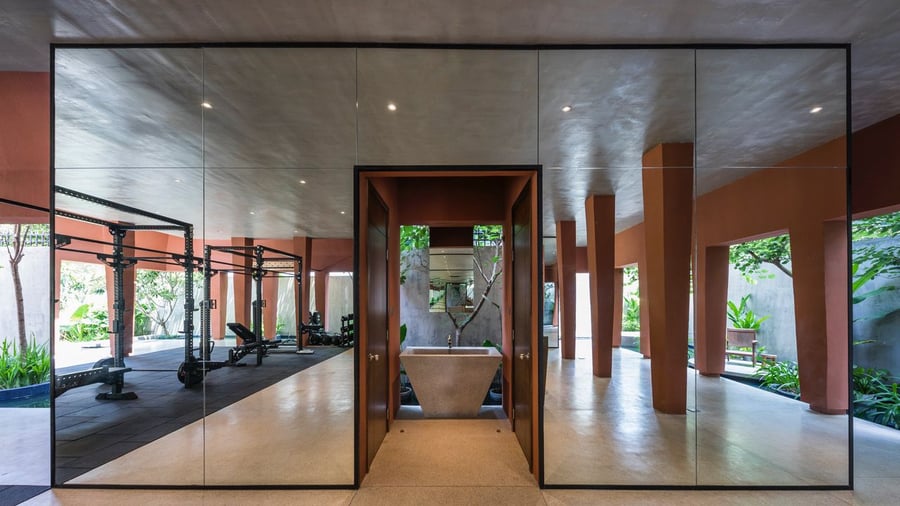 Mirrored fitness space in Ho Chi Minh City's nature-infused Red Cave house. 